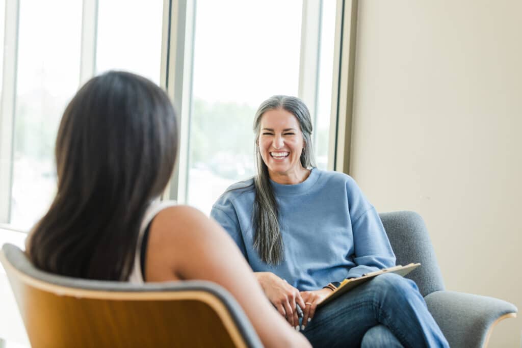 Vrolijke vrouwelijke therapeut en patiënt tijdens een counselinggesprek